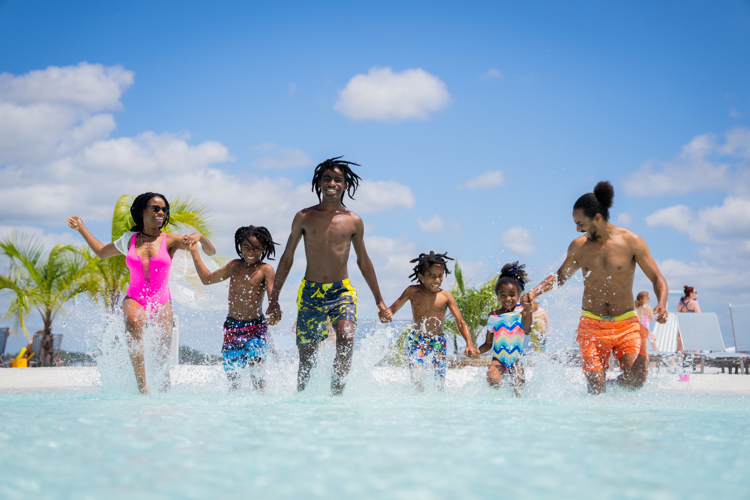Family running hand in hand through the shallow lagoon water