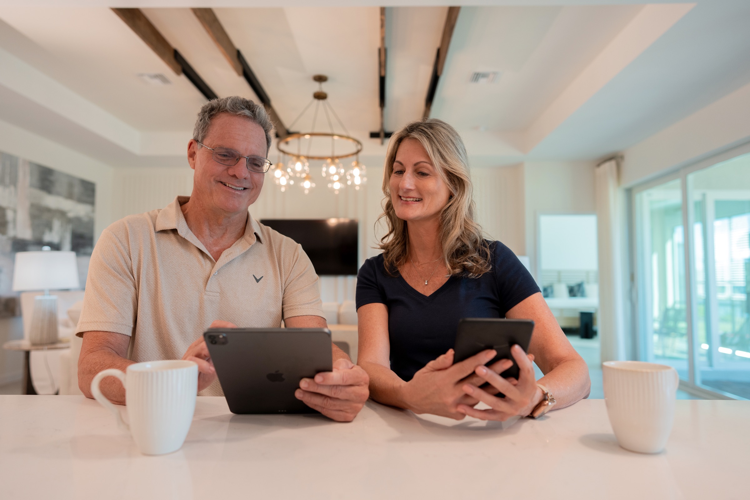 Couple using a tablet and phone at the kitchen island of a Seaire home